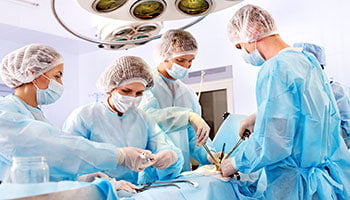 Medical team in surgical attire operating on a patient in a hospital setting