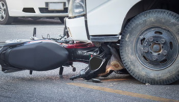 A motorcycle lies on the ground next to a car