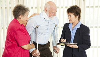 A man with a crutch conversing with two women