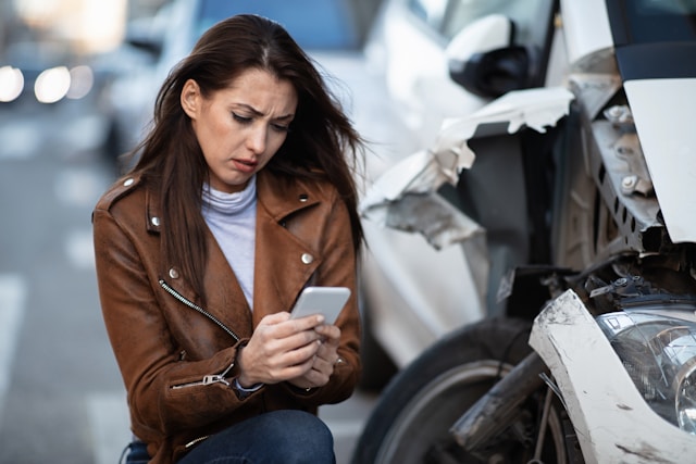woman assessing damage to her car following an accident